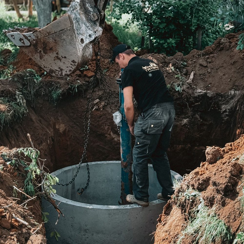 Worker setting a concrete ring in a deep excavation